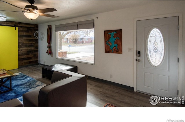 entrance foyer with wood walls, a barn door, ceiling fan, and hardwood / wood-style floors