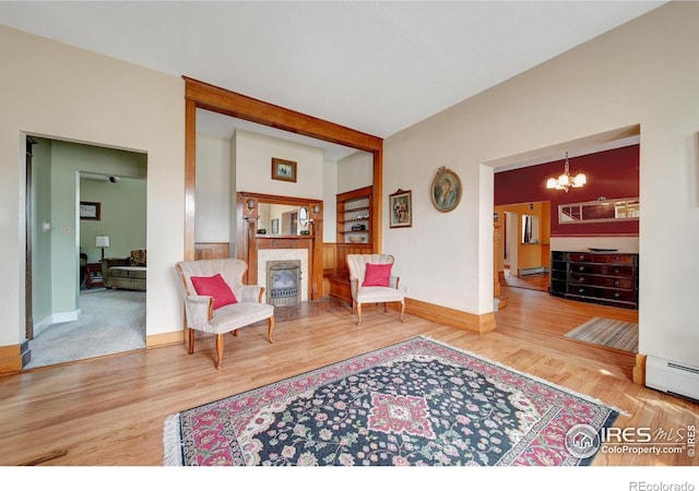 sitting room featuring a notable chandelier, a baseboard heating unit, and hardwood / wood-style flooring