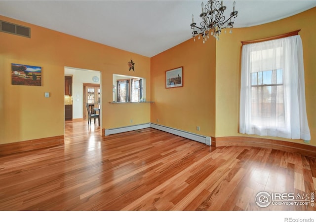 empty room with a notable chandelier, a wealth of natural light, a baseboard radiator, and light wood-type flooring