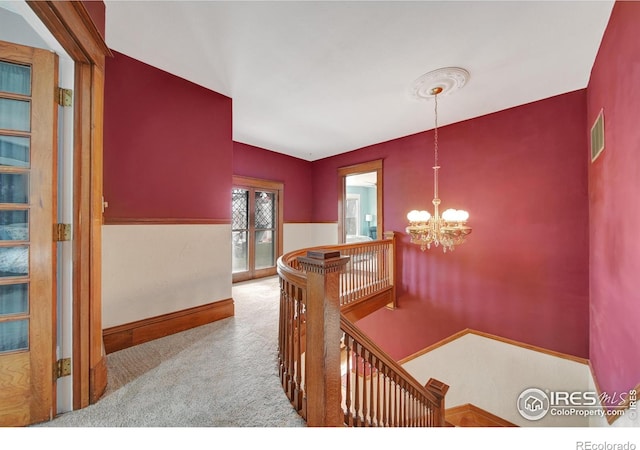 hall featuring light colored carpet and a chandelier