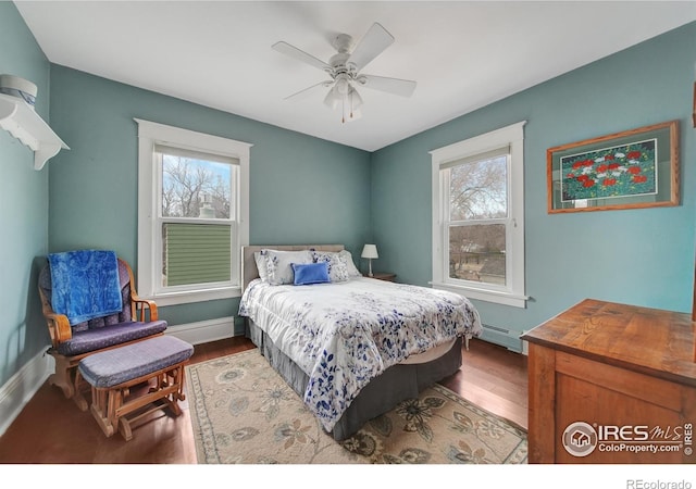 bedroom featuring multiple windows, baseboard heating, hardwood / wood-style floors, and ceiling fan