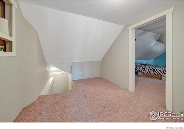 bonus room with lofted ceiling, a textured ceiling, and carpet flooring