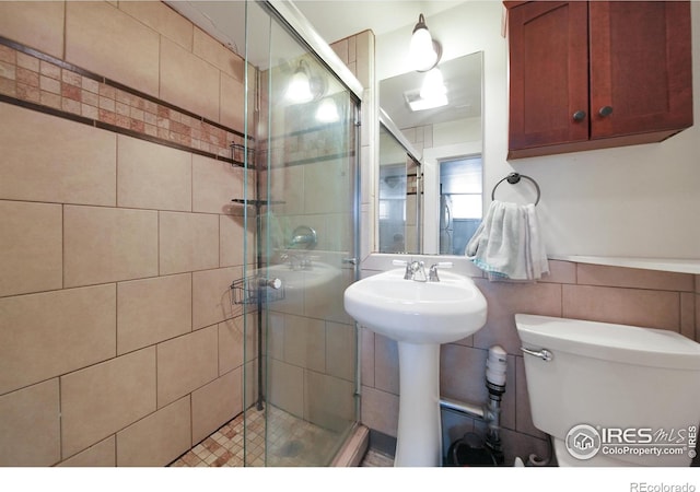 bathroom featuring tile walls, sink, walk in shower, and toilet