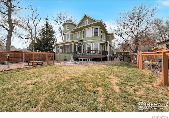 rear view of house featuring a lawn, a sunroom, and a deck