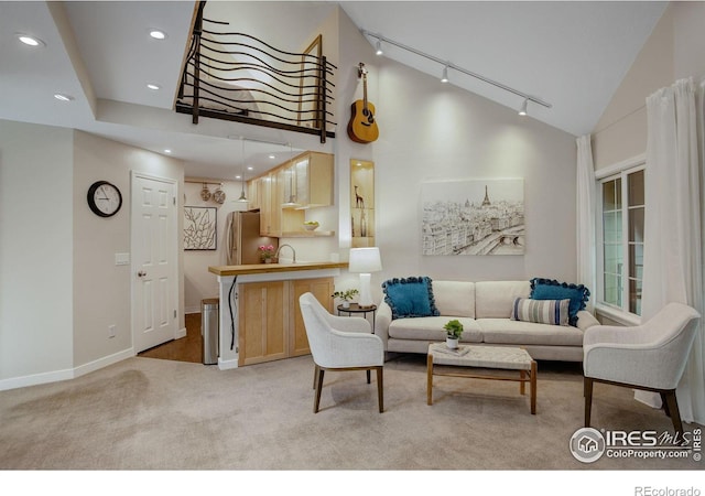 living room with track lighting, light colored carpet, lofted ceiling, and sink