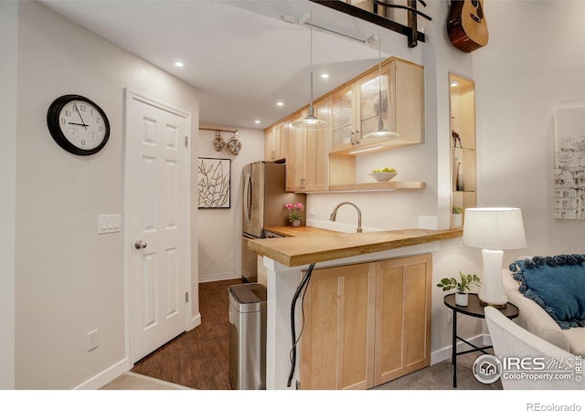 kitchen featuring hanging light fixtures, kitchen peninsula, light brown cabinets, and dark wood-type flooring