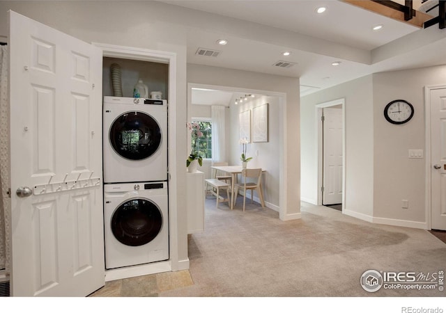 laundry room featuring light carpet and stacked washer / dryer