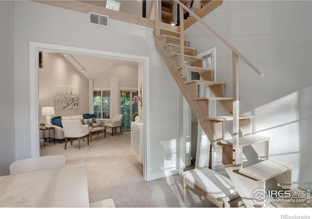 staircase with high vaulted ceiling and carpet