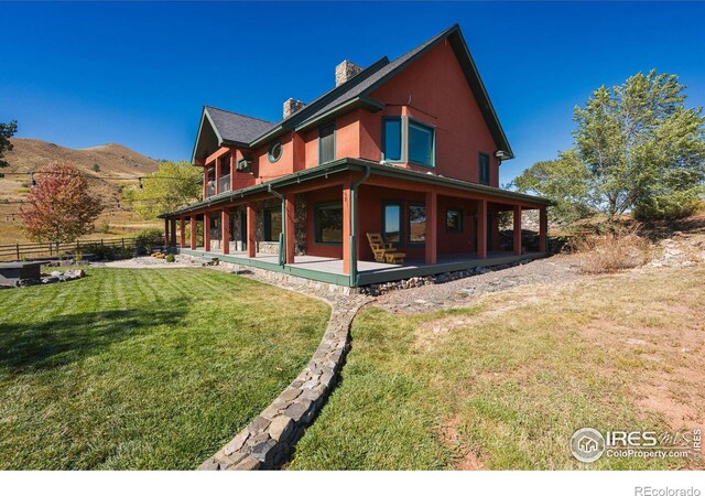 back of house featuring a patio area, a mountain view, and a lawn