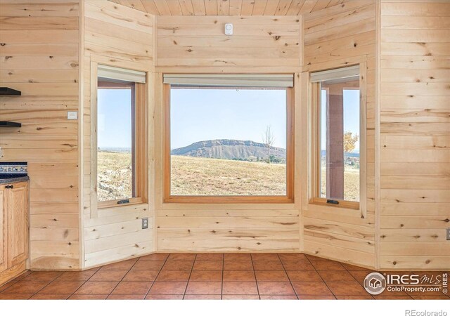 doorway to outside with tile patterned flooring, a mountain view, and wood walls