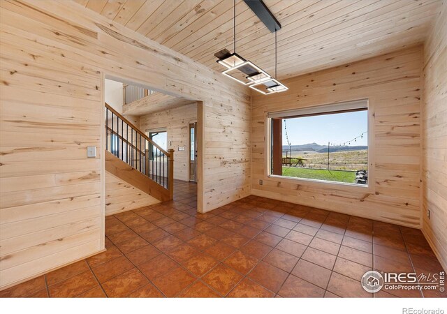 spare room featuring wooden ceiling, a mountain view, wood walls, and dark tile patterned floors