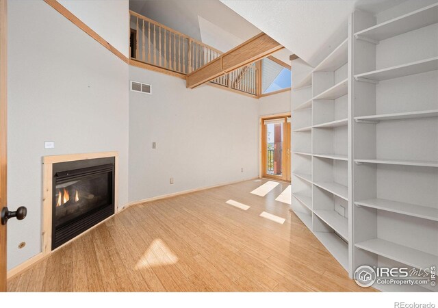 unfurnished living room with a towering ceiling and hardwood / wood-style floors