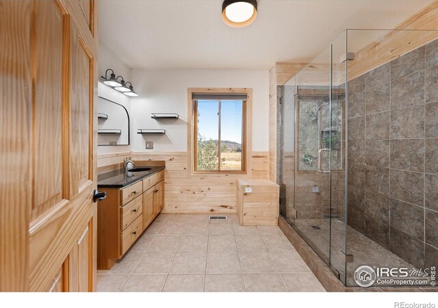 bathroom with vanity, a shower with door, tile patterned floors, and wood walls