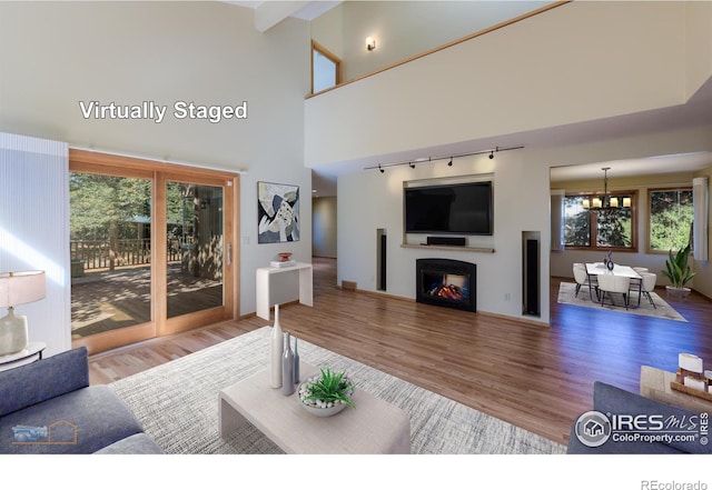 living room with beamed ceiling, a chandelier, high vaulted ceiling, a fireplace, and hardwood / wood-style floors