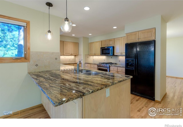 kitchen with kitchen peninsula, light wood-type flooring, black appliances, decorative light fixtures, and dark stone counters