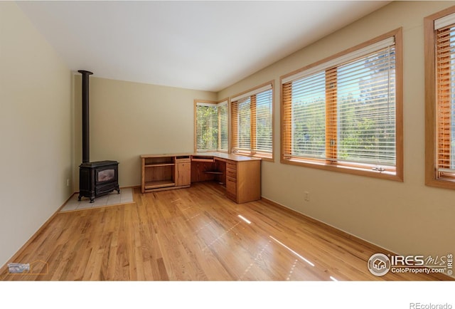 unfurnished office featuring a wood stove and light wood-type flooring