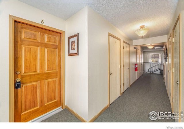 corridor with a textured ceiling and carpet flooring