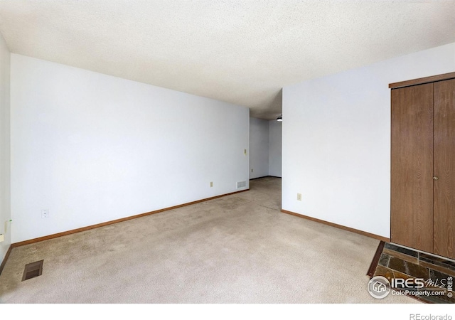 carpeted empty room featuring a textured ceiling