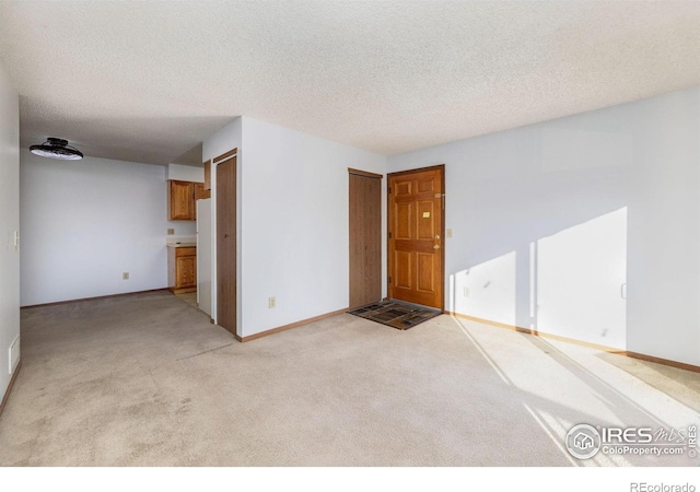 spare room with a textured ceiling and light carpet