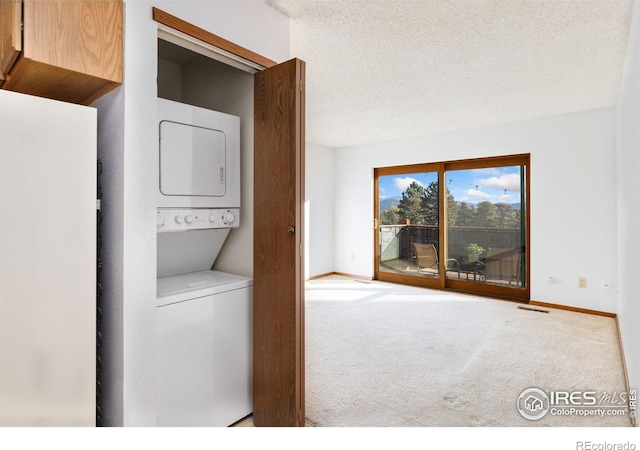 clothes washing area featuring a textured ceiling, stacked washer / drying machine, and carpet floors