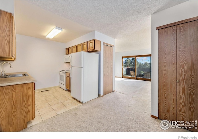 kitchen featuring a textured ceiling, white appliances, sink, and light carpet