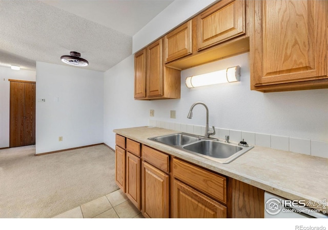 kitchen featuring light carpet, a textured ceiling, and sink