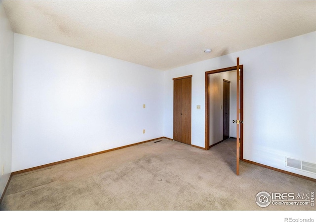 carpeted spare room with a textured ceiling