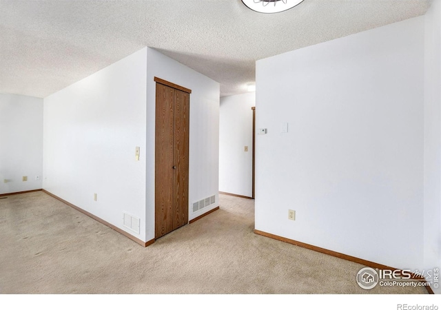 unfurnished room featuring light carpet and a textured ceiling