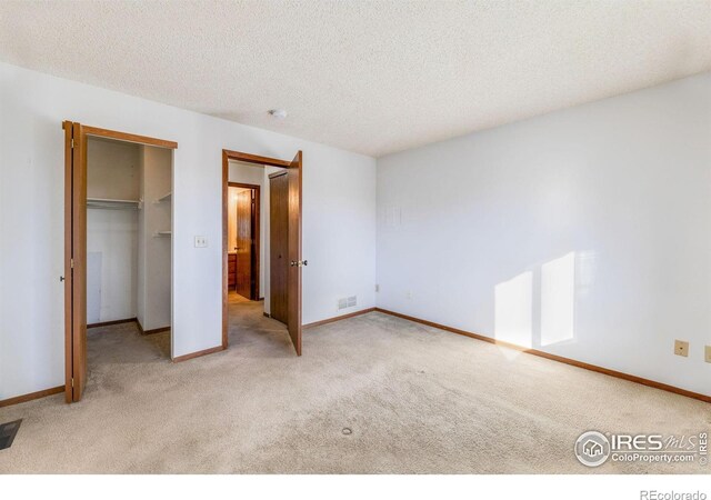 unfurnished bedroom with a textured ceiling, light colored carpet, and a closet