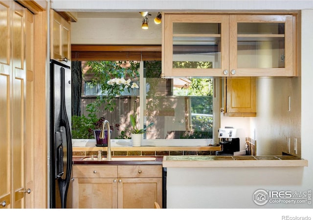 kitchen featuring light brown cabinetry, sink, and black fridge with ice dispenser