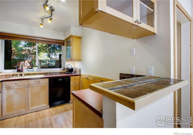 kitchen with tile counters, dishwasher, light wood-type flooring, and sink