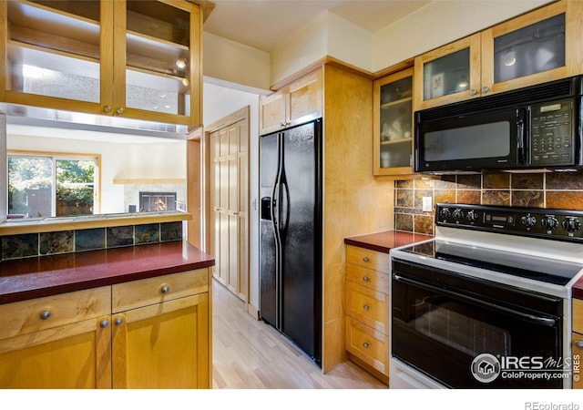 kitchen with black appliances, light hardwood / wood-style floors, and backsplash