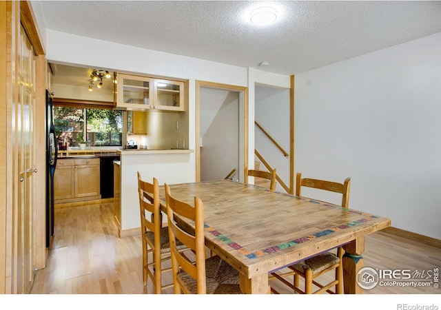 dining room with light wood-type flooring and a textured ceiling