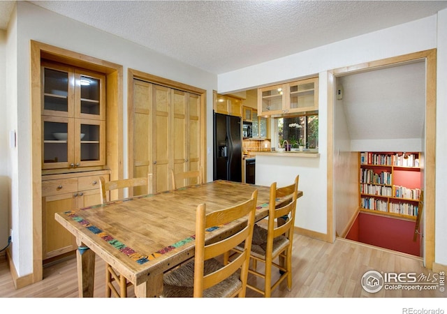 dining room with a textured ceiling, light wood-type flooring, and sink