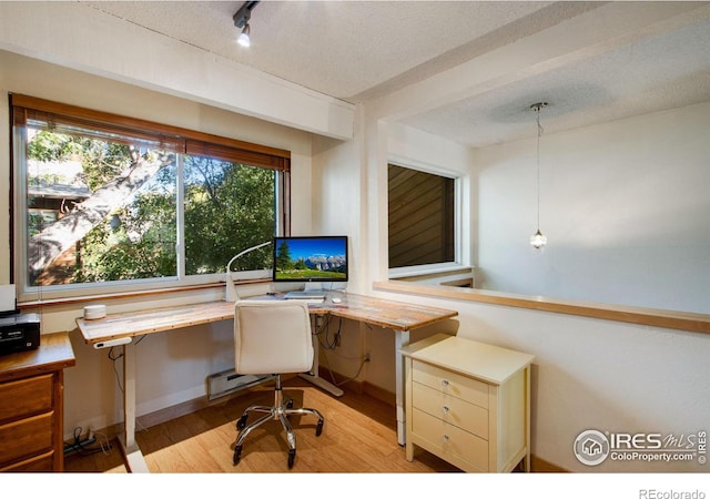 office area featuring a textured ceiling, light wood-type flooring, and built in desk