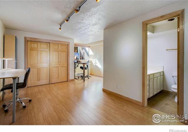 home office with wood-type flooring, rail lighting, and a textured ceiling