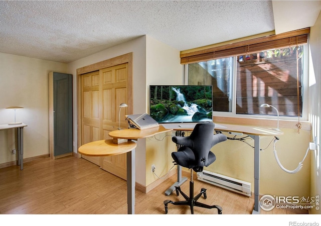 office with light hardwood / wood-style floors, a baseboard heating unit, and a textured ceiling