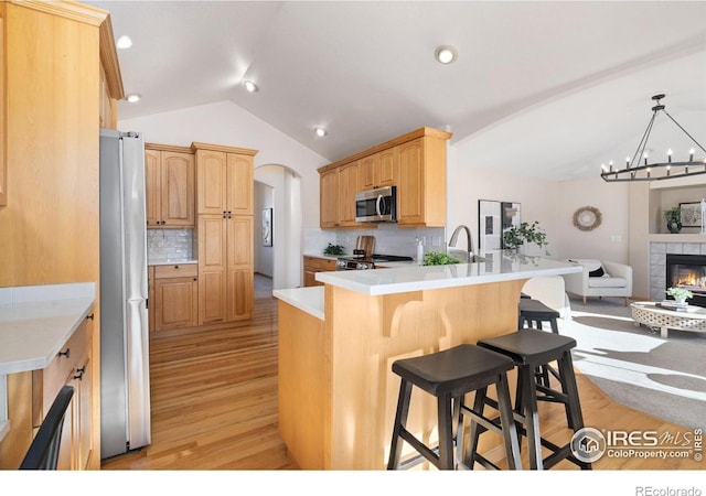 kitchen with light hardwood / wood-style floors, stainless steel appliances, kitchen peninsula, a breakfast bar, and tasteful backsplash