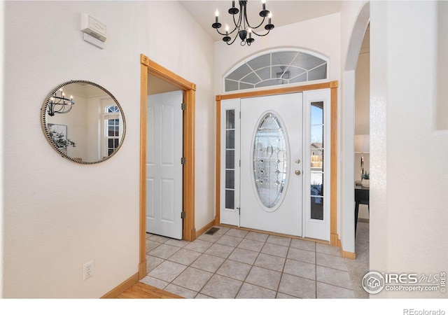 tiled foyer with a chandelier