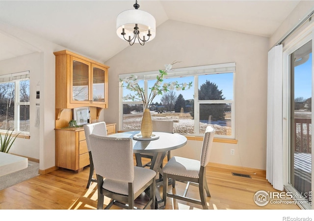 dining space featuring light hardwood / wood-style floors, lofted ceiling, a wealth of natural light, and a chandelier