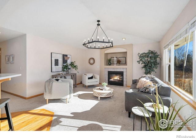 living room with a tile fireplace, a notable chandelier, vaulted ceiling, and carpet