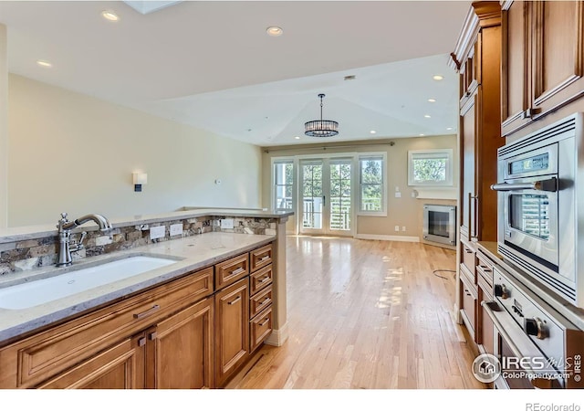 kitchen with light hardwood / wood-style floors, oven, and light stone counters