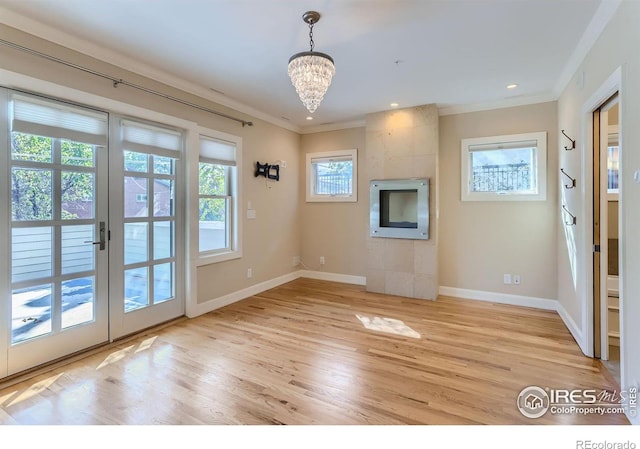 unfurnished living room featuring crown molding, light hardwood / wood-style flooring, and a chandelier