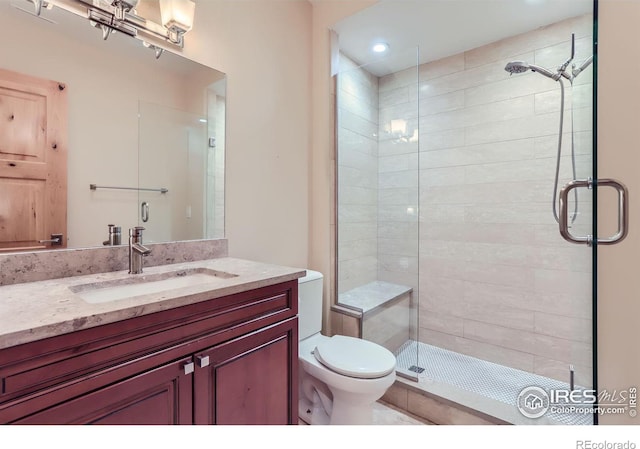 bathroom with a shower with shower door, vanity, and toilet