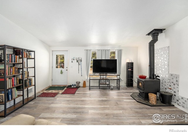 living room with baseboards, wood finished floors, and a wood stove