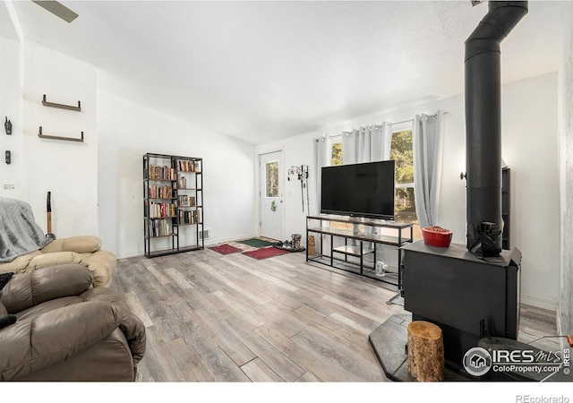 living room featuring vaulted ceiling, wood finished floors, and a wood stove