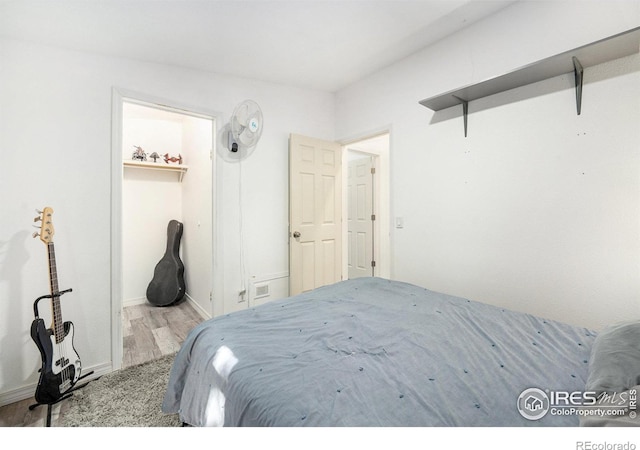 bedroom featuring a spacious closet, wood finished floors, and a closet