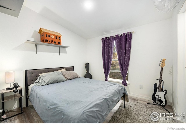 bedroom featuring lofted ceiling, baseboards, and wood finished floors