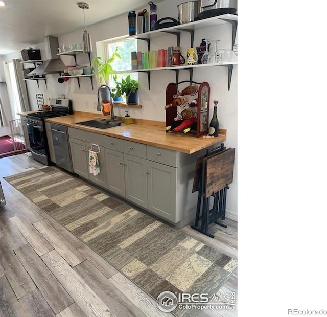 272 Severance Lodge Rd, Black Hawk, CO 80422 - kitchen with open shelves, stainless steel range with gas stovetop, light wood finished floors, wall chimney exhaust hood, and wood counters