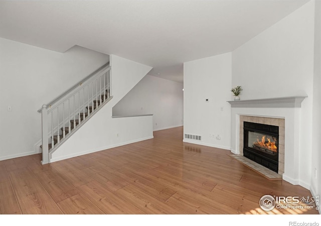 unfurnished living room featuring a tile fireplace and light hardwood / wood-style flooring